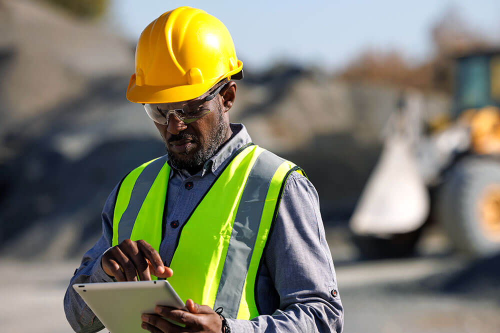 Construction man in hardhat on site using a tablet to work